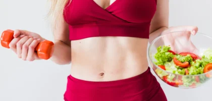 A woman holding a bowl of salad and a carrot.